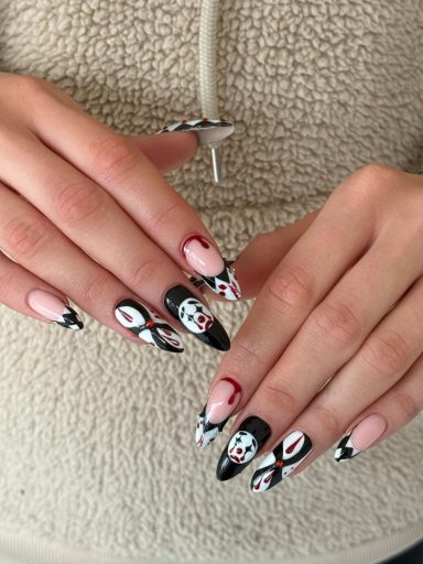Hands with long, decorative nails featuring black, white, and pink designs.