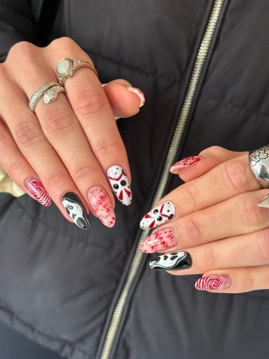 Stylish hands with intricate nail art in pink, black, and white designs.