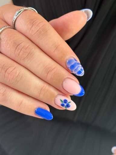 Fashionable nails featuring blue and pink designs, with floral and striped patterns.