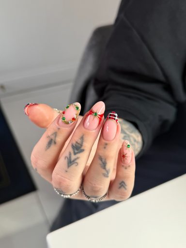 Close-up of a hand with colourful nail art and tattoos.